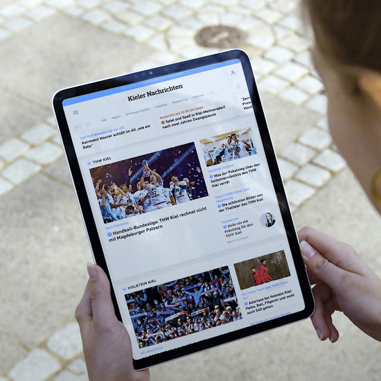 Eine Frau mit einem Tablet, das die Website der Kieler Nachrichten zeigt