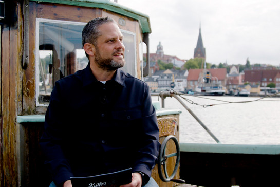 Timo Klass sitzt auf einem hölzernem Schiff