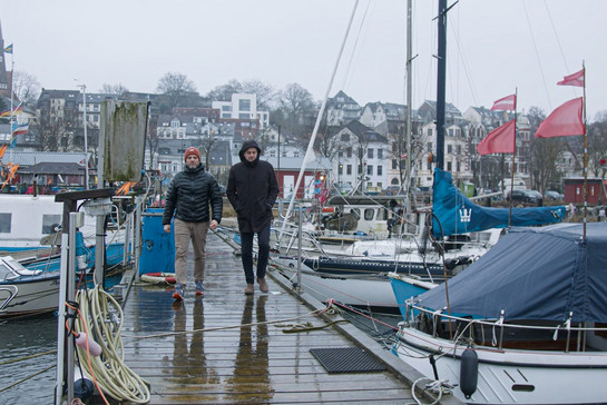 Timo Klass geht mit Peter Cohrs über einen Flensburger Bootssteg
