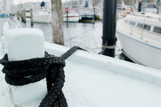 Ein schwarzes Seil festgeknotet an einem Schiff